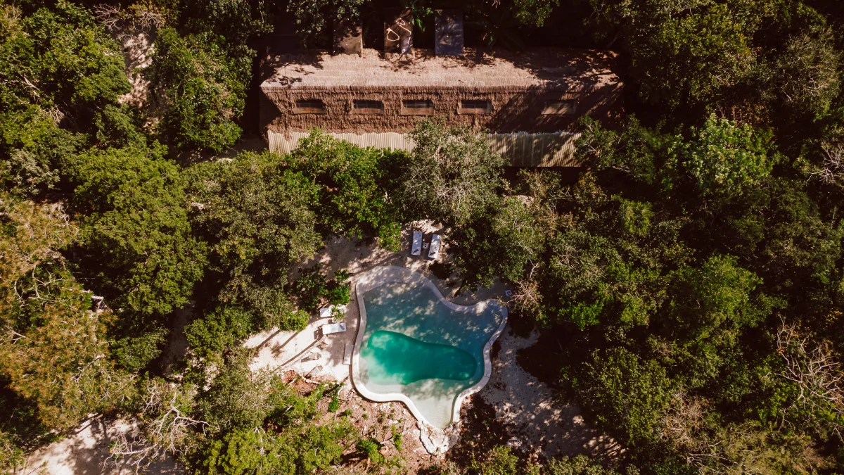 Vista aérea de Casa Arkaana — la veranda principal, la alberca alimentada por cenote y el dosel de la selva en el venue de bodas en la selva de Tulum